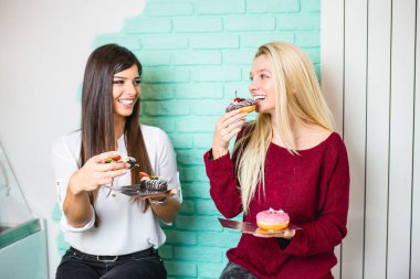 İki güzel genç kadın lezzetli tadını sırlı ve donuts dekore edilmiş. 