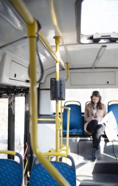 Şehir otobüs içinde oturan, cep telefonu seyir ve müzik güzel mutlu genç kadın.  