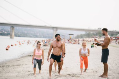 Plajda eğlenmek ve bazı fitness egzersiz yapıyor genç çekici insanların Grubu.