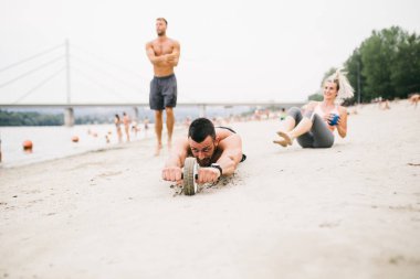 Plajda eğlenmek ve bazı fitness egzersiz yapıyor genç çekici insanların Grubu.