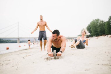 Plajda eğlenmek ve bazı fitness egzersiz yapıyor genç çekici insanların Grubu.
