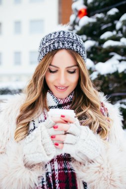 Kış kış, karlı gününde dışarı çıkmak bir kahve tutan güzel kadın portresi.