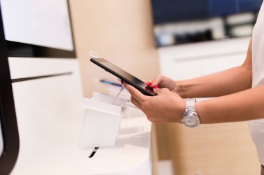 Atış kadın alışveriş cep telefonu kapatın. Mobil olarak duruyor ve dükkanı ve seçimi bir sonraki model onun için tablet. 