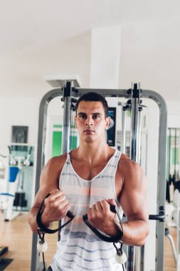 Spor salonunda ağırlık çekici bir genç adam. Fitness, spor ve sağlık kavramı