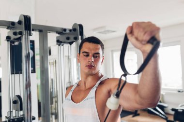 Spor salonunda ağırlık çekici bir genç adam. Fitness, spor ve sağlık kavramı