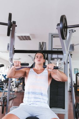 Spor salonunda ağırlık çekici bir genç adam. Fitness, spor ve sağlık kavramı