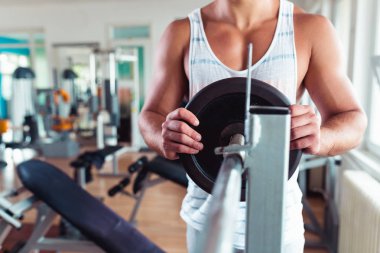 Spor salonunda ağırlık çekici bir genç adam. Fitness, spor ve sağlık kavramı
