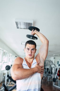 Spor salonunda ağırlık çekici bir genç adam. Fitness, spor ve sağlık kavramı