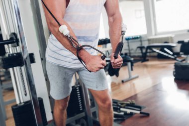 Spor salonunda ağırlık çekici bir genç adam. Fitness, spor ve sağlık kavramı