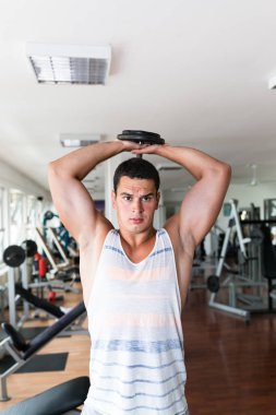 Spor salonunda ağırlık çekici bir genç adam. Fitness, spor ve sağlık kavramı