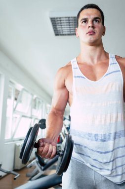 Spor salonunda ağırlık çekici bir genç adam. Fitness, spor ve sağlık kavramı