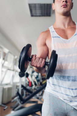 Spor salonunda ağırlık çekici bir genç adam. Fitness, spor ve sağlık kavramı