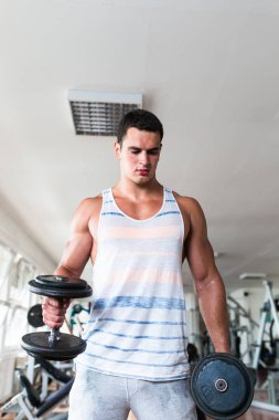 Spor salonunda ağırlık çekici bir genç adam. Fitness, spor ve sağlık kavramı