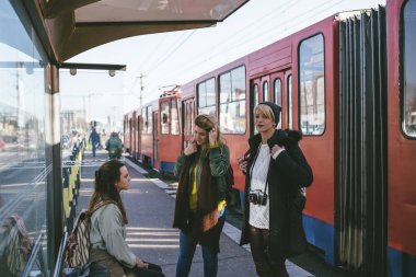 Bir tramvay için bekleyen ve sohbet üç güzel genç kadın, Tramvay İstasyonu.