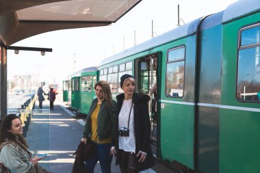 Bir tramvay için bekleyen ve sohbet üç güzel genç kadın, Tramvay İstasyonu.
