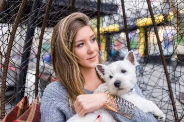 Güzel genç kadın sevimli westie köpek yavrusu ile kafeteryada zevk.