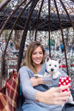 Güzel genç kadın selfie fotoğraf sevimli westie köpek yavrusu alarak.