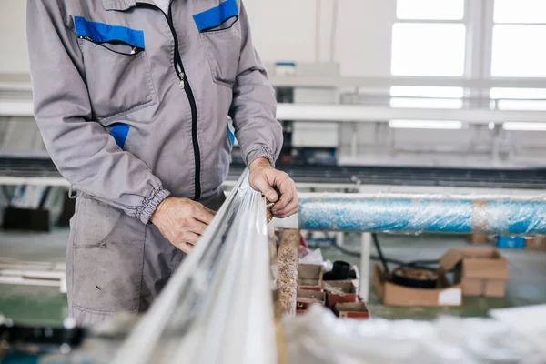 Factory for aluminum and PVC windows and doors production. Manual worker assembling PVC doors and windows