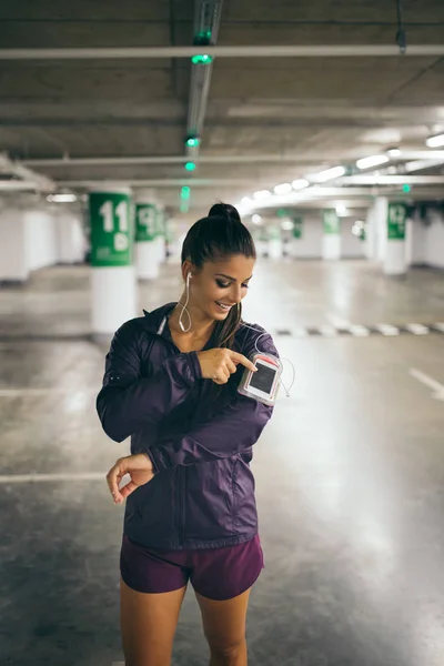 Young woman in public parking garage with earphones listening to music.