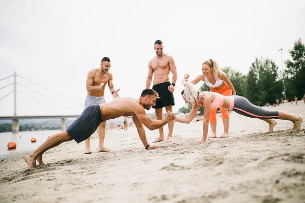 Plajda eğlenmek ve bazı fitness egzersiz yapıyor genç çekici insanların Grubu.