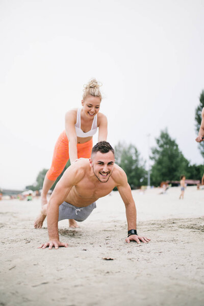 Group of young attractive people having fun at beach and doing some fitness workout.