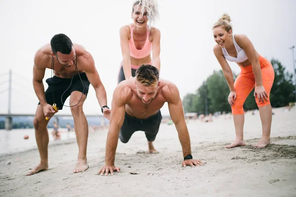 Plajda eğlenmek ve bazı fitness egzersiz yapıyor genç çekici insanların Grubu.