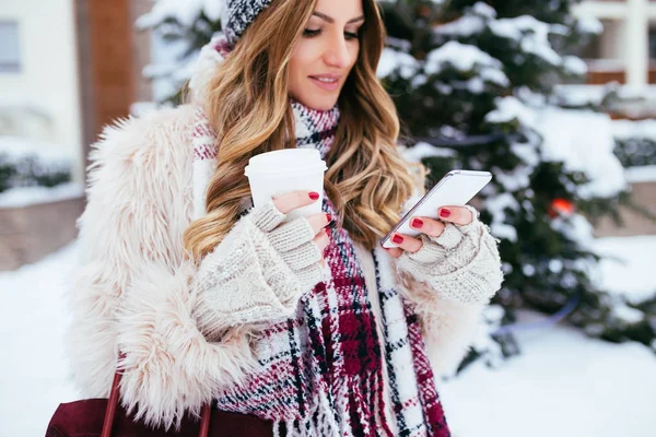 Git ve kış, karlı akıllı telefon dışında seyir için kahve bir gün tutan güzel kadın kış portresi