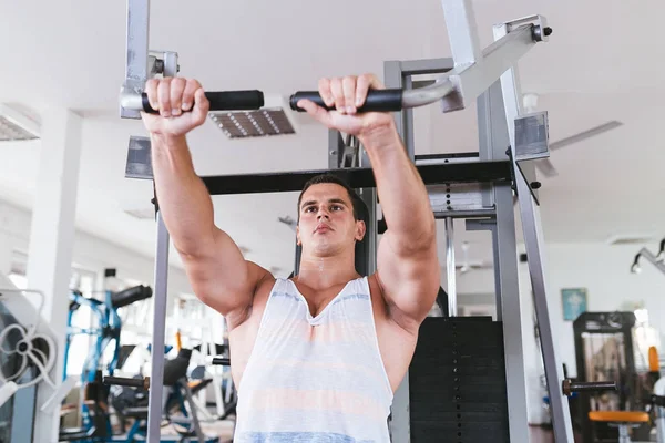 Spor salonunda ağırlık çekici bir genç adam. Fitness, spor ve sağlık kavramı