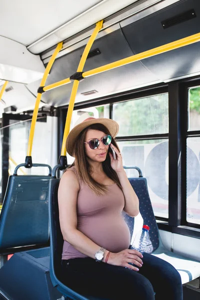 美しい若い妊娠中の女性は 市内バスに座って 携帯電話で話しています — ストック写真