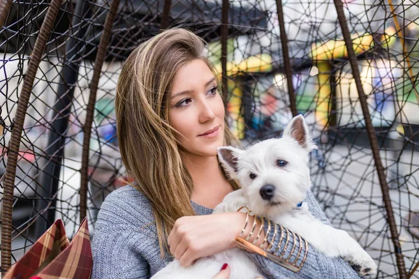 Güzel genç kadın sevimli westie köpek yavrusu ile kafeteryada zevk.