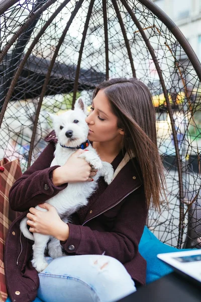 Güzel genç kadın sevimli westie köpek yavrusu ile kafeteryada zevk.