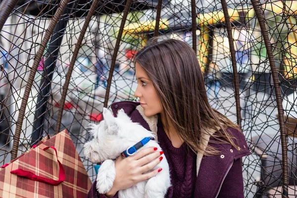 Güzel genç kadın sevimli westie köpek yavrusu ile kafeteryada zevk.