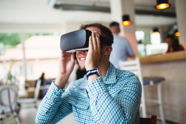 Sanal gerçeklik gözlükleri ile kafe barda oturan genç adam.