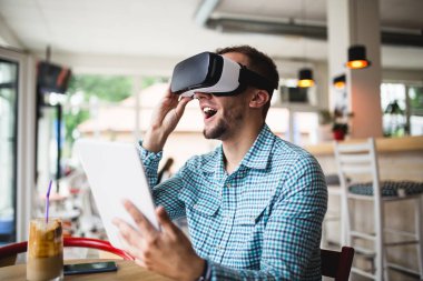Sanal gerçeklik gözlükleri ile kafe barda oturan genç adam 