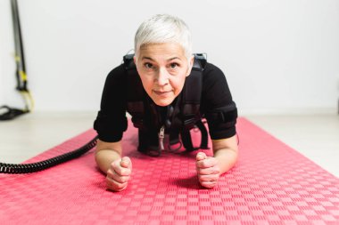 Güzel kadın kıdemli elektrik Kas stimülasyonu elbiseli egzersizleri yapıyor.