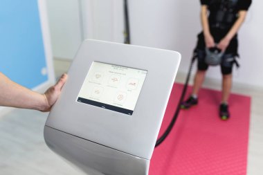 Onu kişisel antrenörü rehabilitasyon merkezi ile elektrik Kas stimülasyonu elbiseli egzersizleri yapıyor kadın.