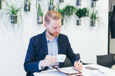 kahve içme ve bir şey onun not defterinde yazıyor redhead iş adamı