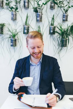 kahve içme ve bir şey onun not defterinde yazıyor redhead iş adamı