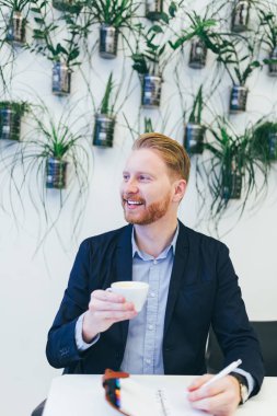 kahve içme ve bir şey onun not defterinde yazıyor redhead iş adamı