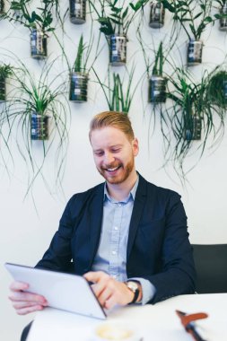 Kendine güvenen genç redhead iş adamı tablet ile çalışma