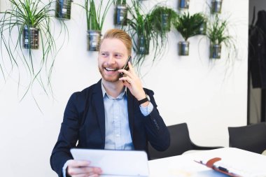 Cep telefonuyla konuşurken ve gülümseyen genç kendinden emin ve mutlu redhead iş adamı