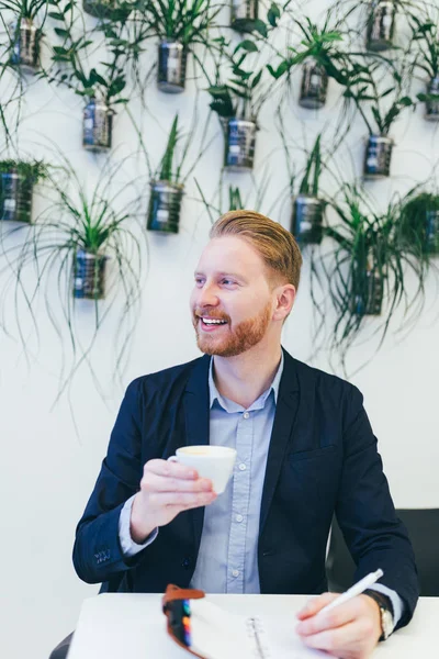 kahve içme ve bir şey onun not defterinde yazıyor redhead iş adamı