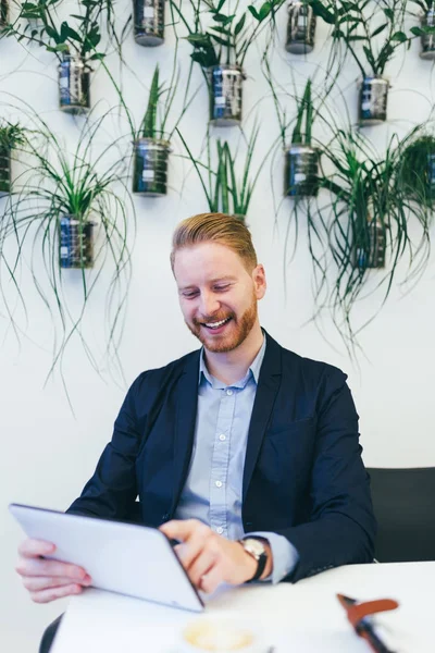 Kendine güvenen genç redhead iş adamı tablet ile çalışma