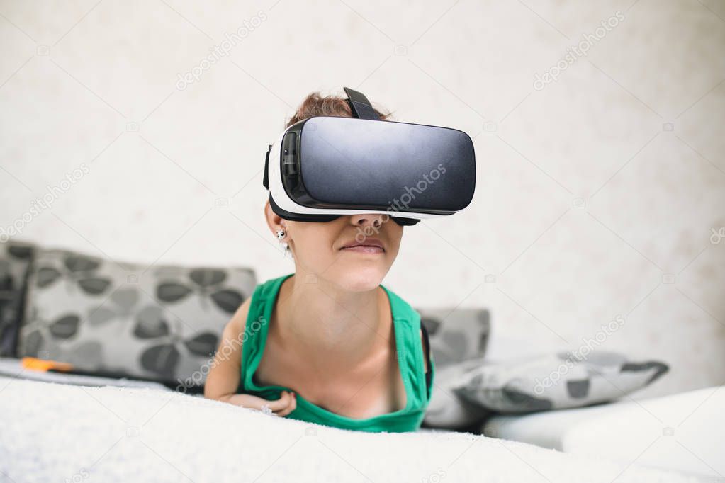 Beautiful disabled young woman with virtual reality goggles sitting on couch and preparing for playing video game. 