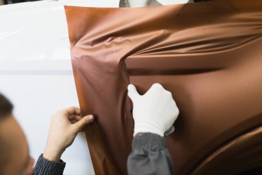 Araba ambalaj uzmanı arabaya vinil folyo ya da film koyuyor. Seçici odak.