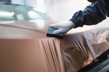 Araba ambalaj uzmanı arabaya vinil folyo ya da film koyuyor. Seçici odak.