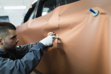 Araba ambalaj uzmanı arabaya vinil folyo ya da film koyuyor. Seçici odak.