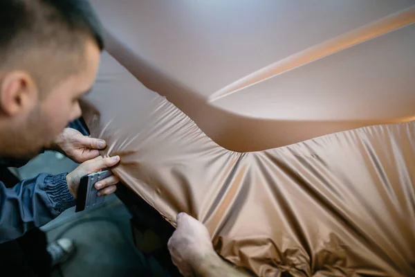 Araba ambalaj uzmanı arabaya vinil folyo ya da film koyuyor. Seçici odak.