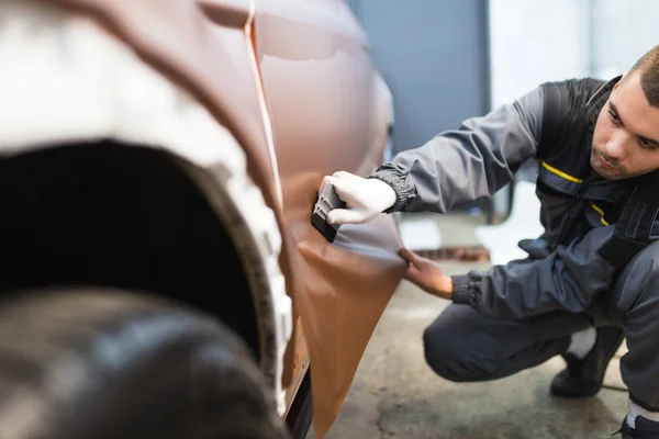 Araba ambalaj uzmanı arabaya vinil folyo ya da film koyuyor. Seçici odak.