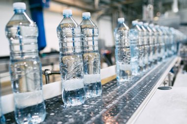 Şişeleme tesisi - Su şişeleme hattı saf kaynak suyunu işlemek ve şişelemek için mavi şişelere. Seçici odak. 